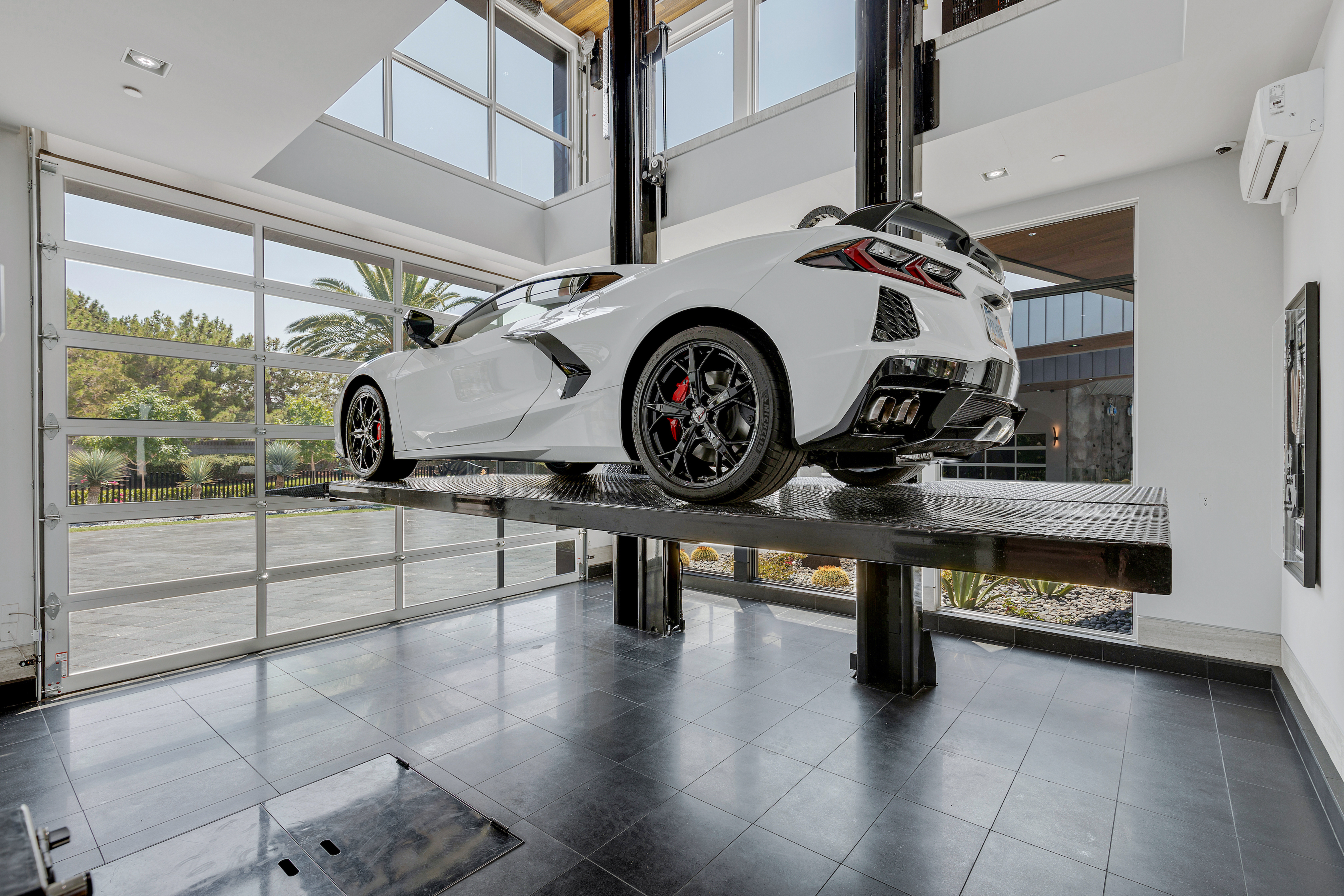 White sports car elevated on indoor car lift.