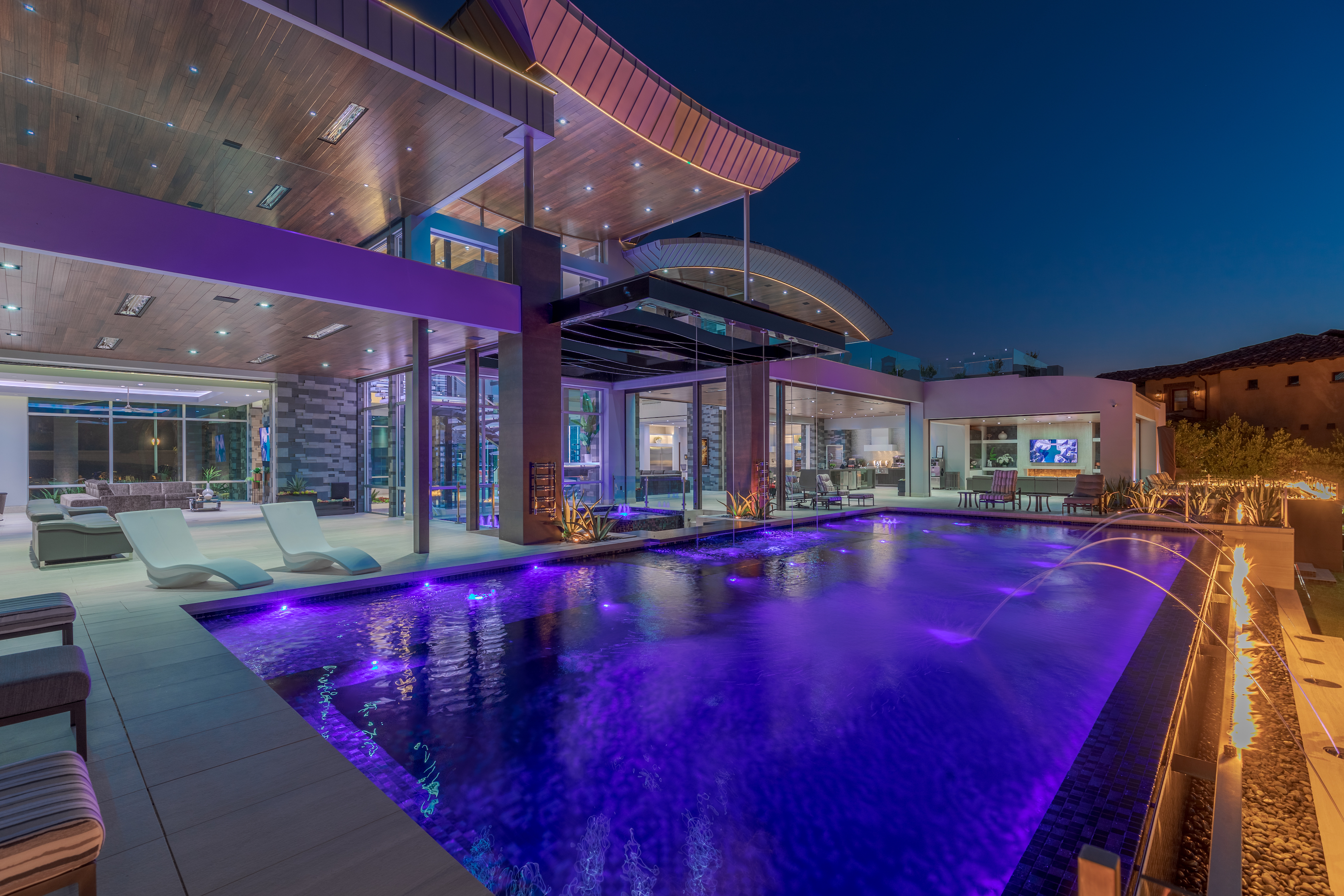 LED-lit pool at night with parallel fireplace.
